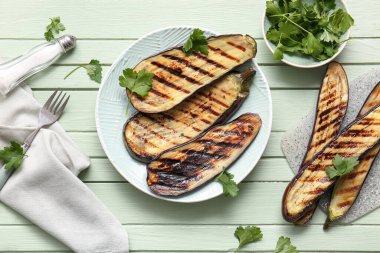 Lezzetli ızgara patlıcan tabağı ve yeşil ahşap arka planda maydanoz.