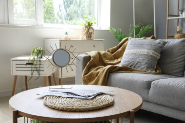 Ayna, hasır hasırlı ahşap sehpa ve oturma odasındaki kanepenin yanındaki dergiler.