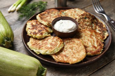 Ahşap arka planda ekşi kremalı bir tabak lezzetli kabaklı börek.