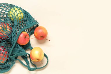 Bej arkaplanlı taze elmalı ağ torbası, yakın plan.