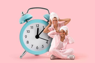 Mutlu Afro-Amerikalı anne ve kızı duş sonrası pijamalarıyla pembe arka planda göz altı yamalarıyla