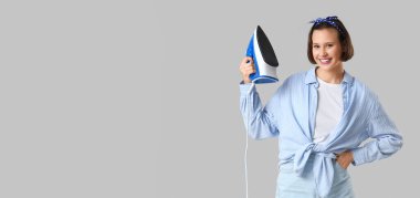 Gri arka planda demiri olan gülümseyen genç kadın.