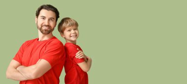 Yeşil arka planda gülümseyen baba ve oğlunun portresi. Babalar Günü.