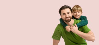 Gülümseyen çocuk pembe arka planda babasına sarılıp mesaj atıyor. Babalar Günü.