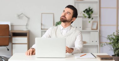 Ofiste masada oturan düşünceli bir işadamı.