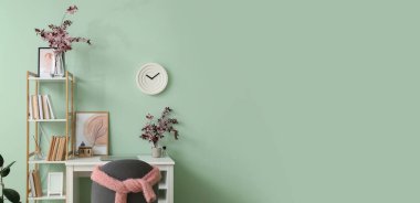 Renk duvarının yanında çiçek açan dalları olan şık bir iş yeri.