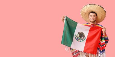 Meksika bayrağını pembe arka planda tutan sombrero 'lu yakışıklı genç adam.