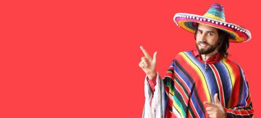 Sombrero ve pançolu yakışıklı genç adam kırmızı arka planda mesaj için yeri olan bir şeye bakıyor.