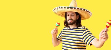 Sombrero 'lu yakışıklı Meksikalı genç adam sarı arka planda marakas çalıyor ve mesaj için yer var.