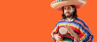 Sombrero ve pançolu yakışıklı Meksikalı genç adam turuncu arka planda davul çalıyor.