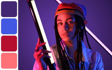 Koyu mor arka planda neon lambaları olan genç bir Afro-Amerikalı kadın. Farklı renk desenleri