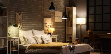 Karanlık yatak odasının içinde gece lambaları, kahve fincanı ve yatağında kitaplar vardı.