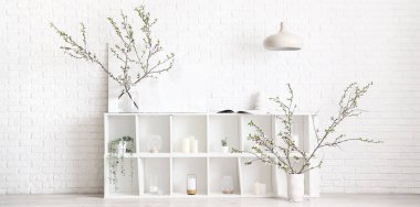 Beyaz tuğla duvarın yanındaki raflarda çiçek açan vazolar.