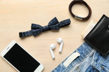 Şık erkek papyonu, cep telefonu, cüzdan ve kotlu kompozisyon açık ahşap arka plan, yakın plan