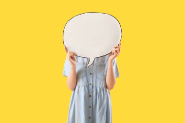 Sarı arka planda boş konuşma balonunun arkasına saklanan genç bir kadın.