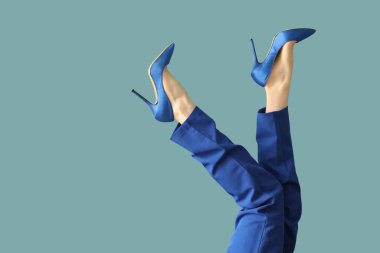 Mavi arka planda zarif yüksek topuklu genç kadın bacakları.