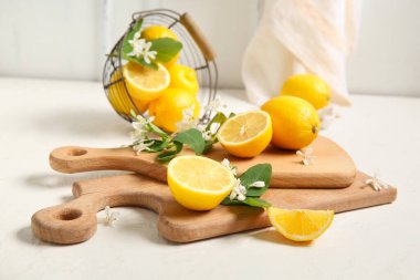 Beyaz masada çiçek açan dalları olan tahtalar ve limon sepeti.