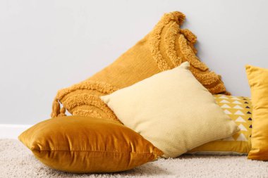 Halıda şık yastıklar, ışık duvarının yanında.