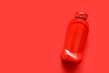 Kırmızı arkaplanda bir şişe ketçap.