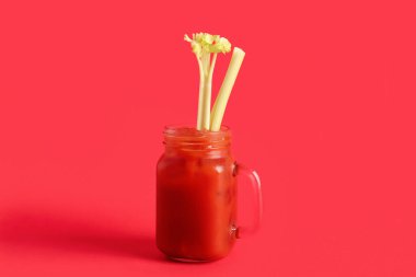 Kırmızı zemin üzerinde kereviz olan bir kavanoz Bloody Mary.