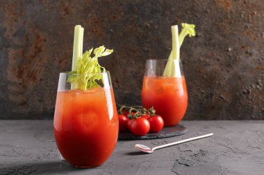 Gri masadaki domatesli ve kerevizli Bloody Mary bardakları
