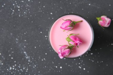 Bir bardak panna cotta ve siyah masanın üzerinde güzel pembe güller.