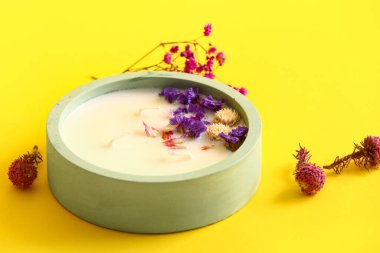 Sarı arka planda mumlu ve çiçekli tutucu