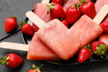 Siyah ahşap arka planda çilekli dondurma tepsisi.