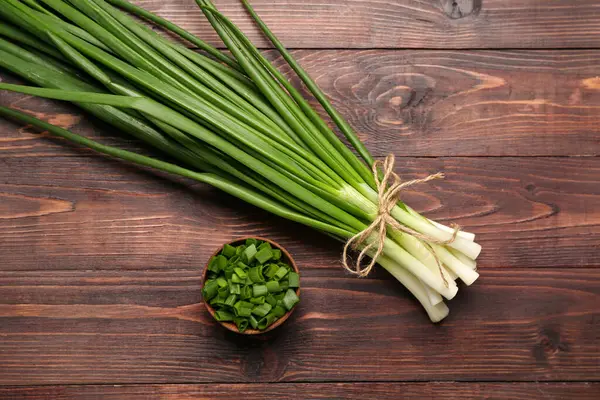 Bir demet taze soğan ve ahşap arka planda kesilmiş kase.