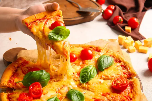 Bir kadın beyaz masada lezzetli bir pizza alıyor.