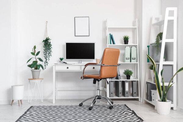 Interior of office with modern workplace, shelving units and artificial plants