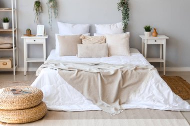 Cozy bed with soft pillows in interior of light bedroom