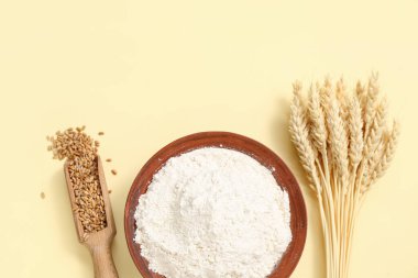 Sarı arka planda buğday unu, kepçe ve çivili kase.