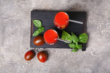 Gri arkaplanda bir bardak lezzetli domates suyu