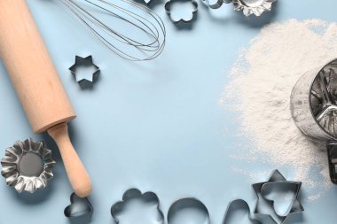 Mavi arkaplanda pişirme aletleri ve kurabiye kesicilerden yapılmış çerçeve