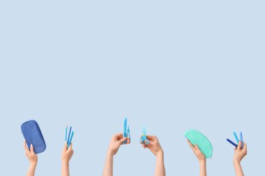 Hands with school supplies on blue background