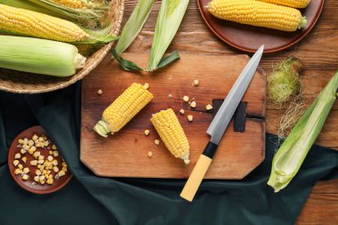 Tahta ve hasır sepette tahtadan yapılmış taze mısır koçanları var.