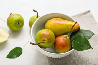 Beyaz masada olgun armutlarla dolu bir kase.