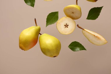 Gri arka planda taze armut ve yapraklar uçuşuyor.