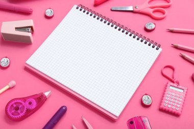 Pembe arka planda farklı kırtasiye malzemesi içeren defter.