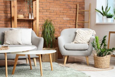 Oturma odasının içinde koltuk, kanepe ve çiçek var.