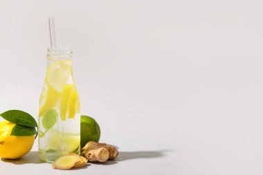 Limonlu bir şişe lezzetli limonata ve beyaz arka planda zencefil.
