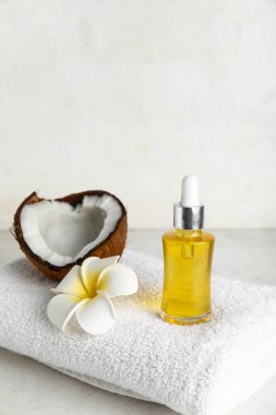 Bir şişe hindistan cevizi kozmetik yağı ve beyaz arka planda banyo havlusu.