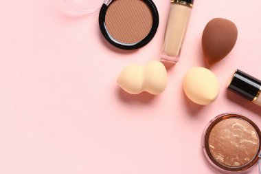 Pembe arka planda makyaj süngerleri ve dekoratif kozmetikler