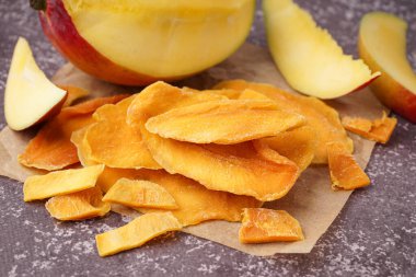 Koyu masa üzerinde kurutulmuş mango dilimleri olan kağıt fırını.