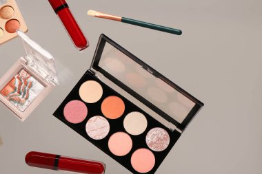 Bej arka planda uçan dekoratif kozmetik ürünleri