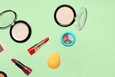 Yeşil arka planda uçan dekoratif kozmetik ürünleri