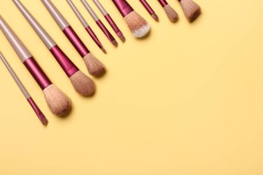 Sarı arkaplanda makyaj fırçaları