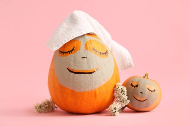 Kil maskeli balkabakları ve pembe arka planda çiçekler