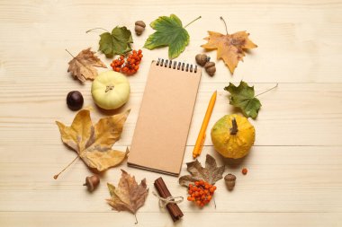 Kahverengi ahşap arka planda defter, balkabağı ve sonbahar yapraklarıyla kompozisyon